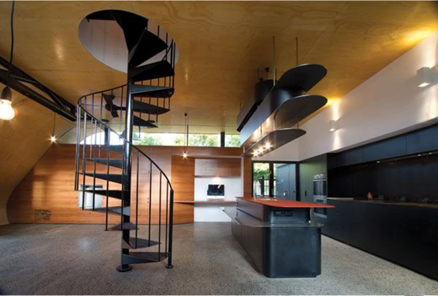 חלל המטבח שבמבנה החדש, והמדרגות הלולייניות הממוקמות במרכז המרחב ומובילות מעלה אל יחידת השינה של ההורים.