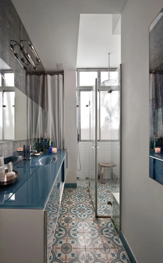 חדר הרחצה: ריצוף באריחי בטון מצוירים, מקלחון שקוף ומפנק, משטח כיור מזכוכית צבעונית ומראות כמובן.