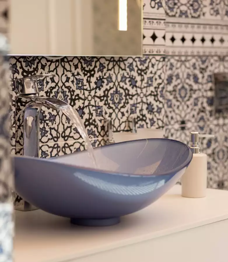 חדר אמבטיה - כיור זכוכית בצבע תכלת המזכיר את צבע אריחי הקיר.