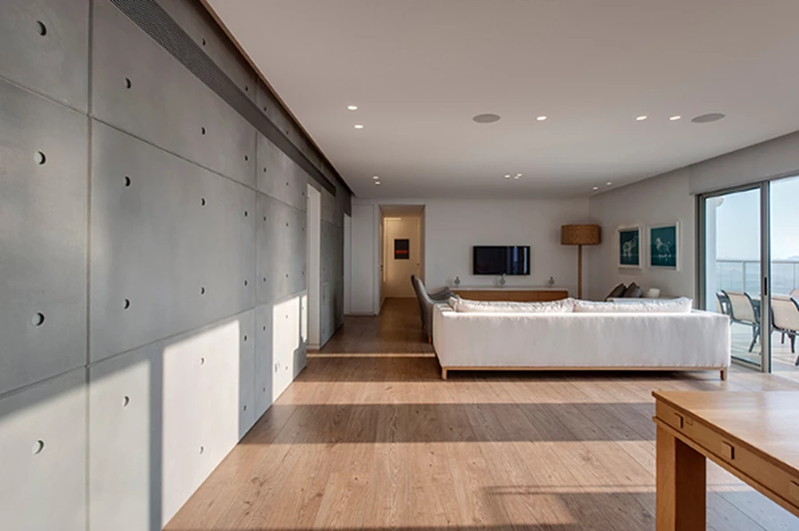חלל מגורים מודרני בדירת גג בה משולבים חיפוי קיר מלוחות בטון עם רצפת עץ (צילום: עודד סמדר)