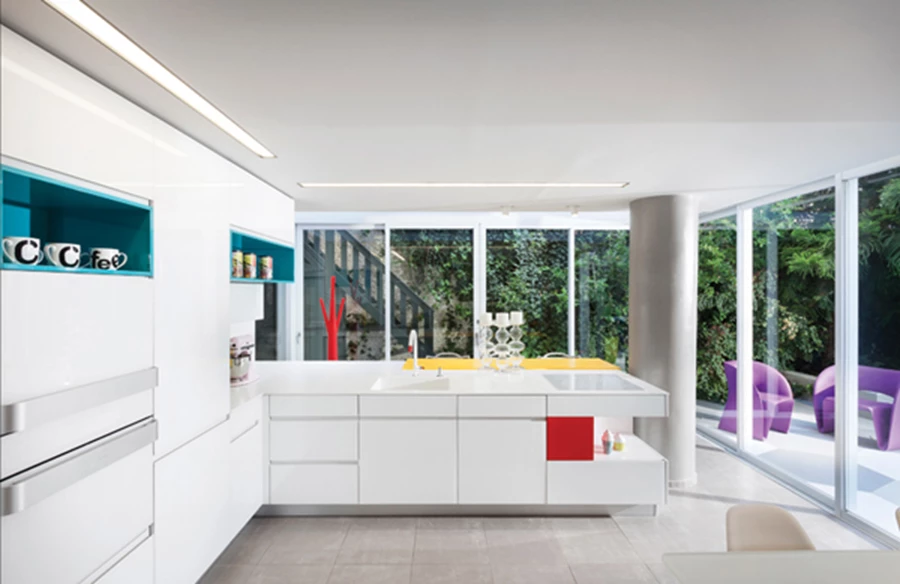 מבט מהסלון לכיוון המטבח: מעוצב בתצורת האות ר' עם חזיתות זכוכית לבנות ומשטח עבודה מקוריאן. בתוך ה