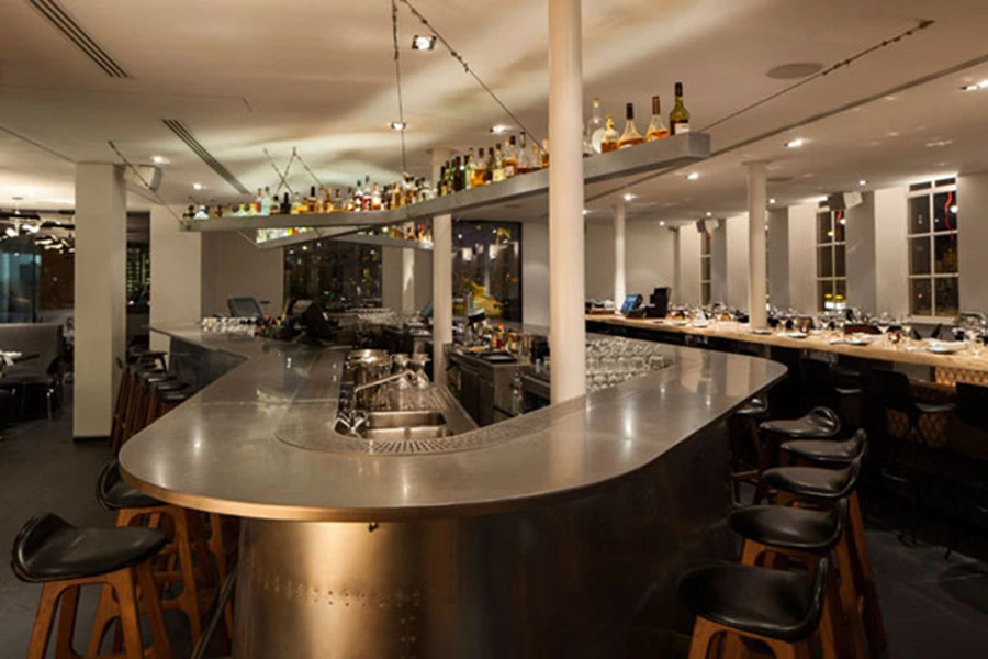 האלמנט המרכזי בחלל חדר האוכל/מסעדה: בר ענק בקונפיגורציה של 360 מעלות מעוצב על טהרת שימוש חוזר בחתיכות אבץ.