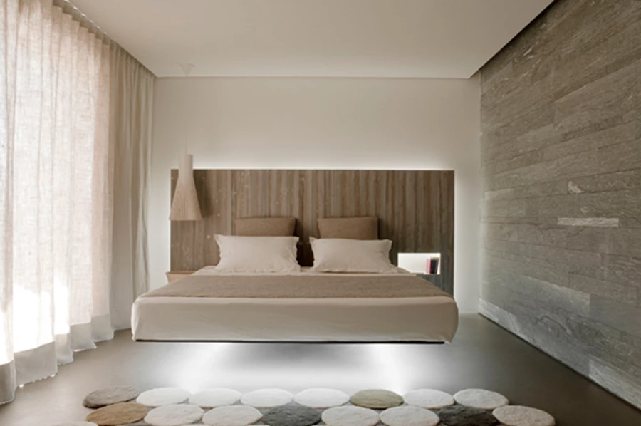 חדר השינה המשלב מיטה מוגבהת מן הרצפה וריצוף העשוי מבטון מוחלק.