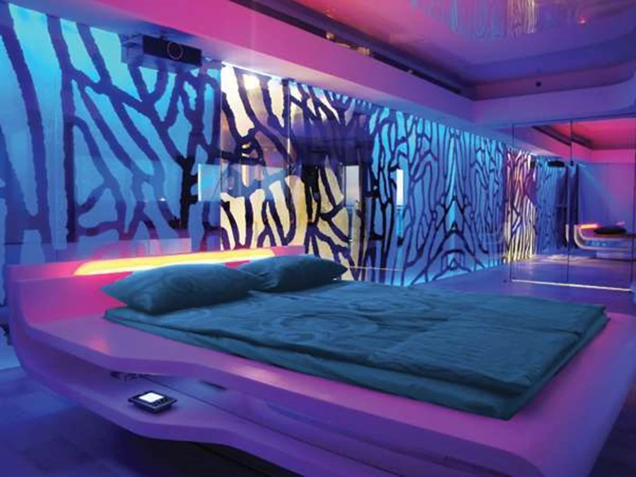 חדר שינה מעוצב- קיר הזכוכית שמאחורי המיטה מצניע מאחוריו חדר ארונות, סאונה רטובה, סאונה יבשה ושירותים.