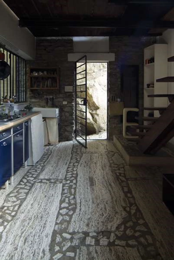 הכניסה לבית שעוברת דרך המטבח שנבנה מאלמנטים שלוקטו אקראית. הריצוף הוא הריצוף המקורי שעשוי מאבן טרוורטין עם פוגות של בטון מבריק.