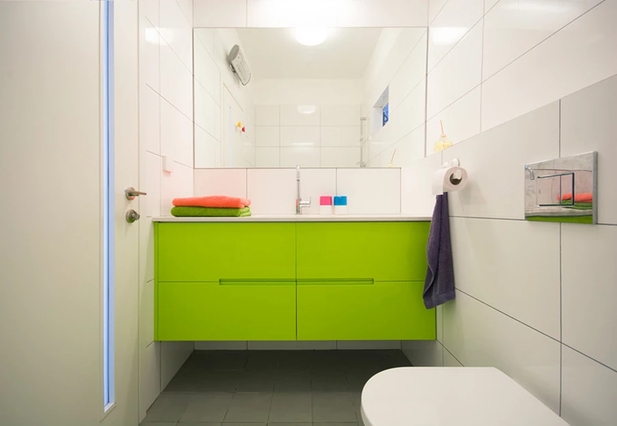 ארון רחצה ירוק מוסיף צבע לחדר אמבטיה ילדים המשמש גם כשרותי אורחים.