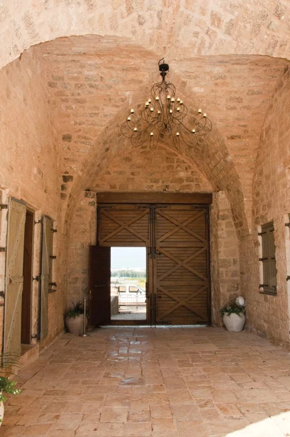 הכניסה למתחם החאן: שער עשוי פלדת קורטן מצטט בחזותו החיצונית שער מחומת עכו מאותה תקופה.